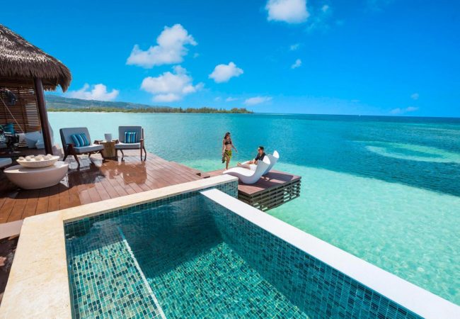 over the water villa at sandals royal caribbean guests relaxing on the balcony of the over the water villas in the caribbean