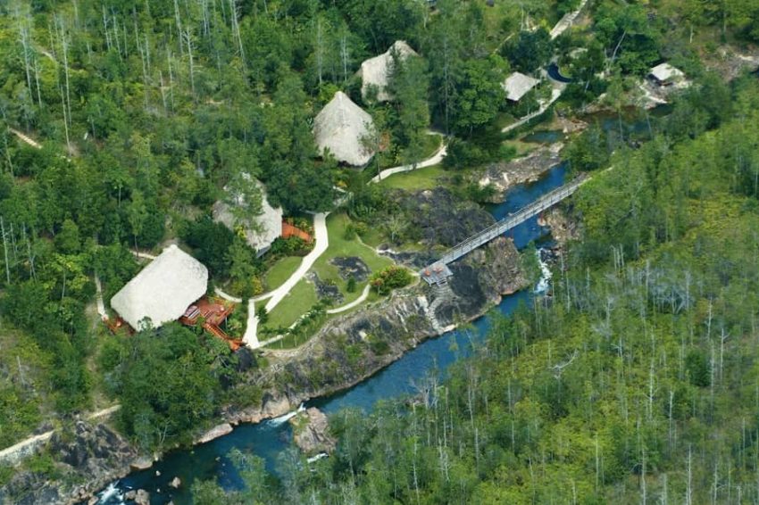 aerial view of blancaneaux lodge in the pine forest next to a creek in belize