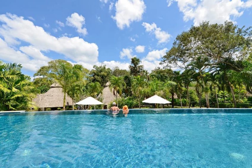 The Lodge at Chaa Creek, Western Belize guests relaxing at the end of the eco infinity pool that overlooks the jungle of belize at chaa creek