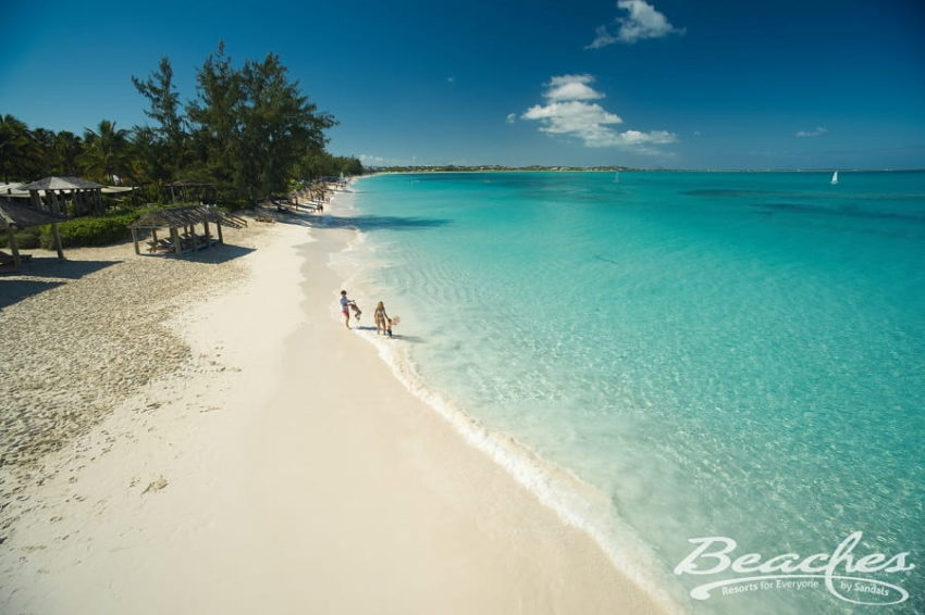 Beaches Turks & Caicos, Turks & Caicos Family Resort family walking on the beach next to cyrstal clear caribbean waters at beaches turks & caicos