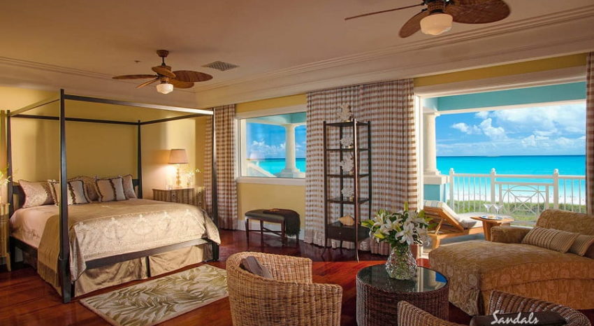 the bed, sitting chair and balcony overlooking the caribbean sea from the royal estate beachfront two story one bedroom bulter villa at sandals emerald bay in the bahamas